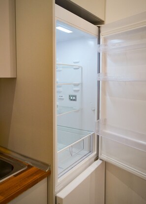 Een keuken met een ingebouwde koelkast, een houten aanrechtblad en een in de muur gemonteerde oven.