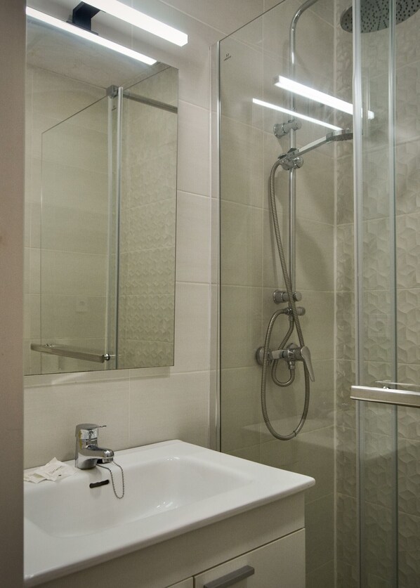 Une salle de bain avec une douche à parois de verre, un lavabo blanc et un miroir au-dessus du lavabo.
