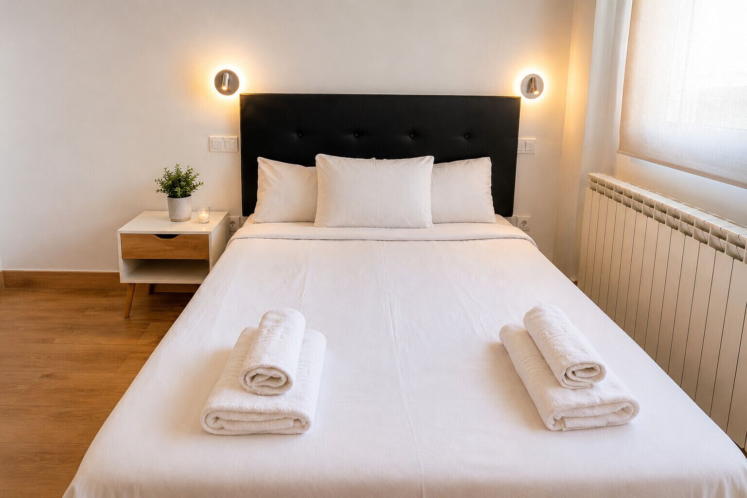 Een hotelkamer met een bed, nachtkastjes, een potplant en een radiator.
