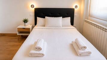 Een hotelkamer met een bed, nachtkastjes, een potplant en een radiator.