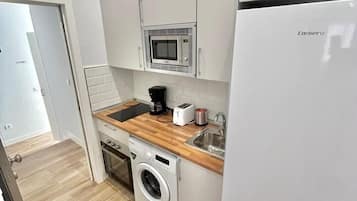 Een kleine keuken met een wasmachine, magnetron en broodrooster.