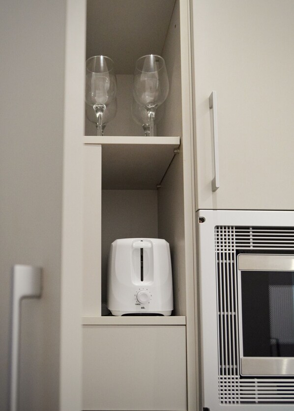 A kitchen with a toaster and two wine glasses on a shelf.