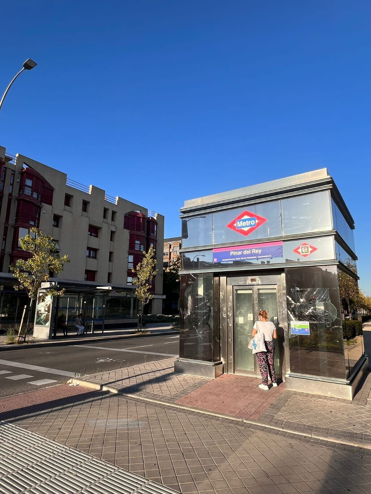Een metrostation met een helderblauwe lucht, een bushalte en een gebouw met het Metro-logo.
