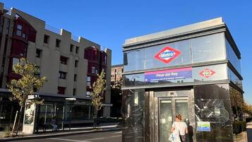 Een metrostation met een helderblauwe lucht, een bushalte en een gebouw met het Metro-logo.
