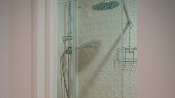 Un baño con ducha, lavabo y perchero para toallas.