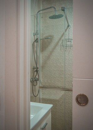 A bathroom with a shower, a sink, and a towel rack.