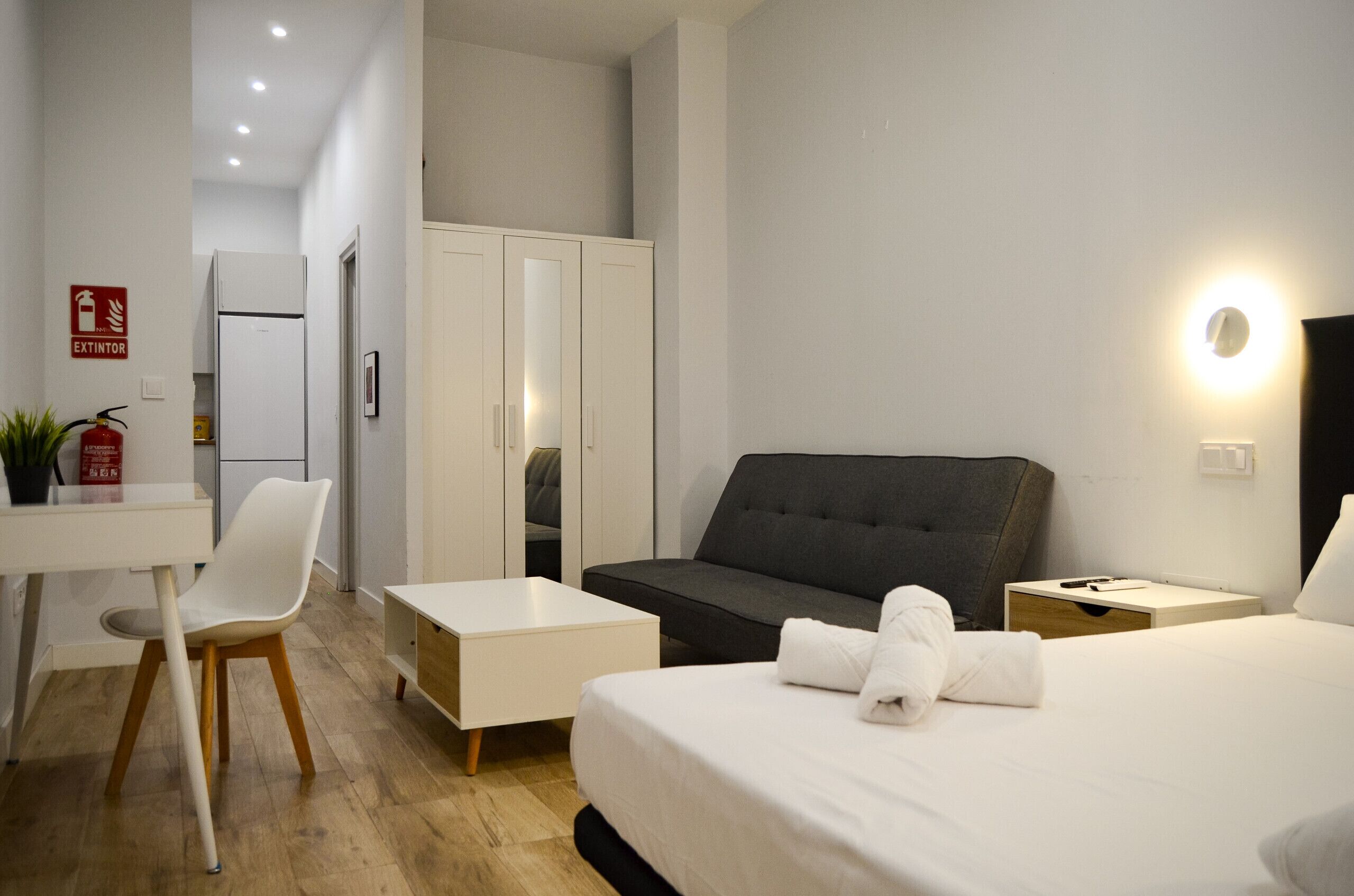 Habitación de hotel con cama, escritorio, silla, sofá y armario.