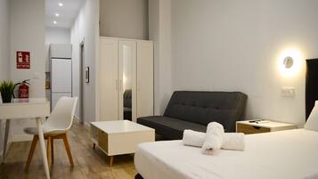 Habitación de hotel con cama, escritorio, silla, sofá y armario.