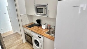 Cocina compacta con lavadora, microondas y tostadora.
