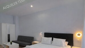 Una habitación de hotel moderna con una cama grande, un sofá, un armario y una mesita de noche.