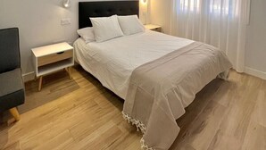 Un dormitorio con cama, mesitas de noche y una ventana con cortinas.