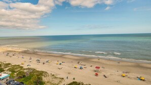 A beach with umbrellas and people. - The Caravelle Resort (Myrtle Beach)