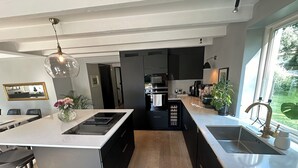Uma cozinha moderna com ilha central, armários pretos e vista para a área de jantar.