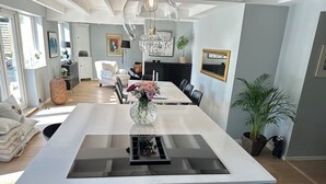 Cozinha moderna com ilha central, espaço de refeições com cadeiras e um candelabro.