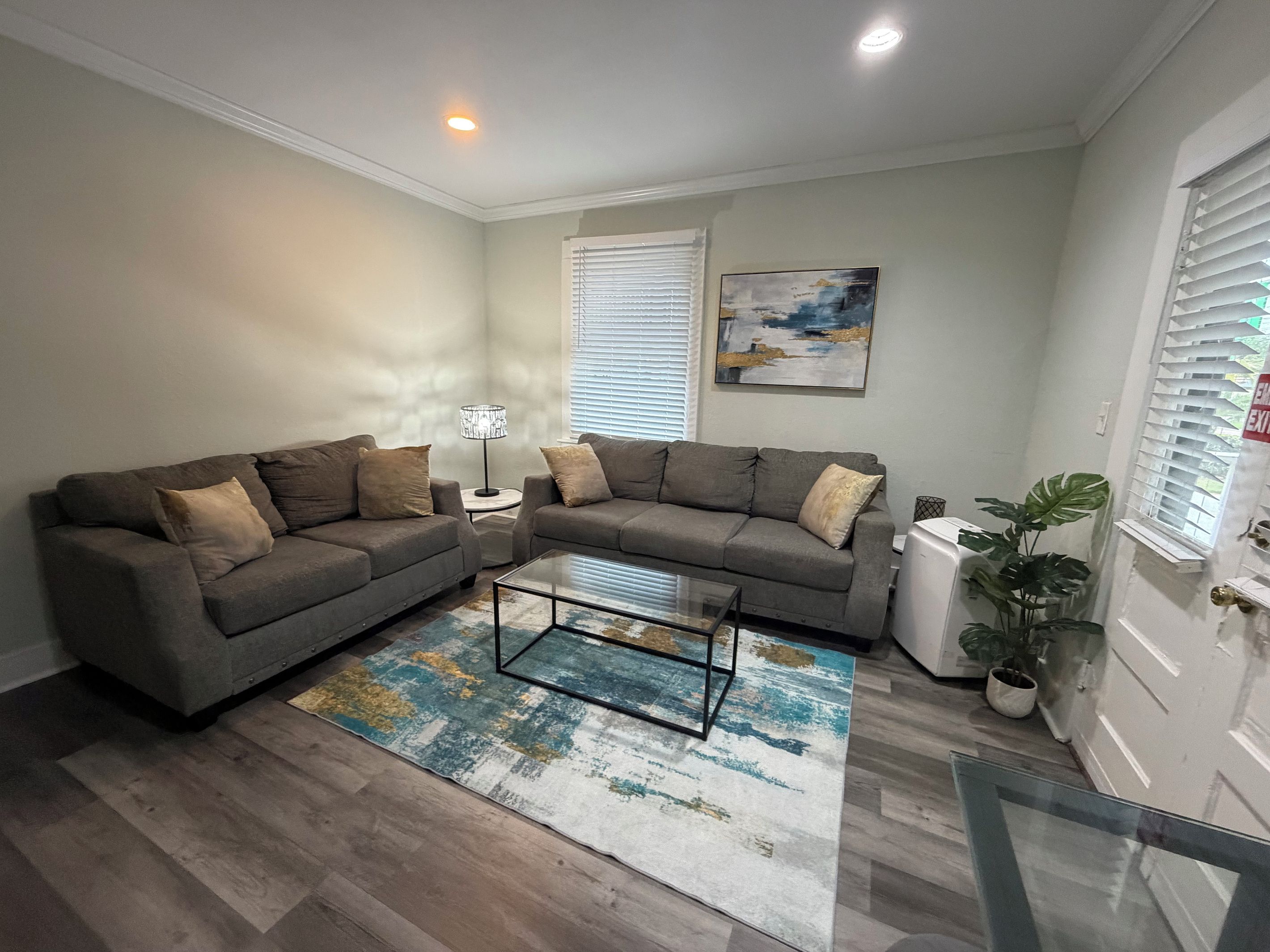 A living room with two sofas, a coffee table, a lamp, a painting, and a potted plant.