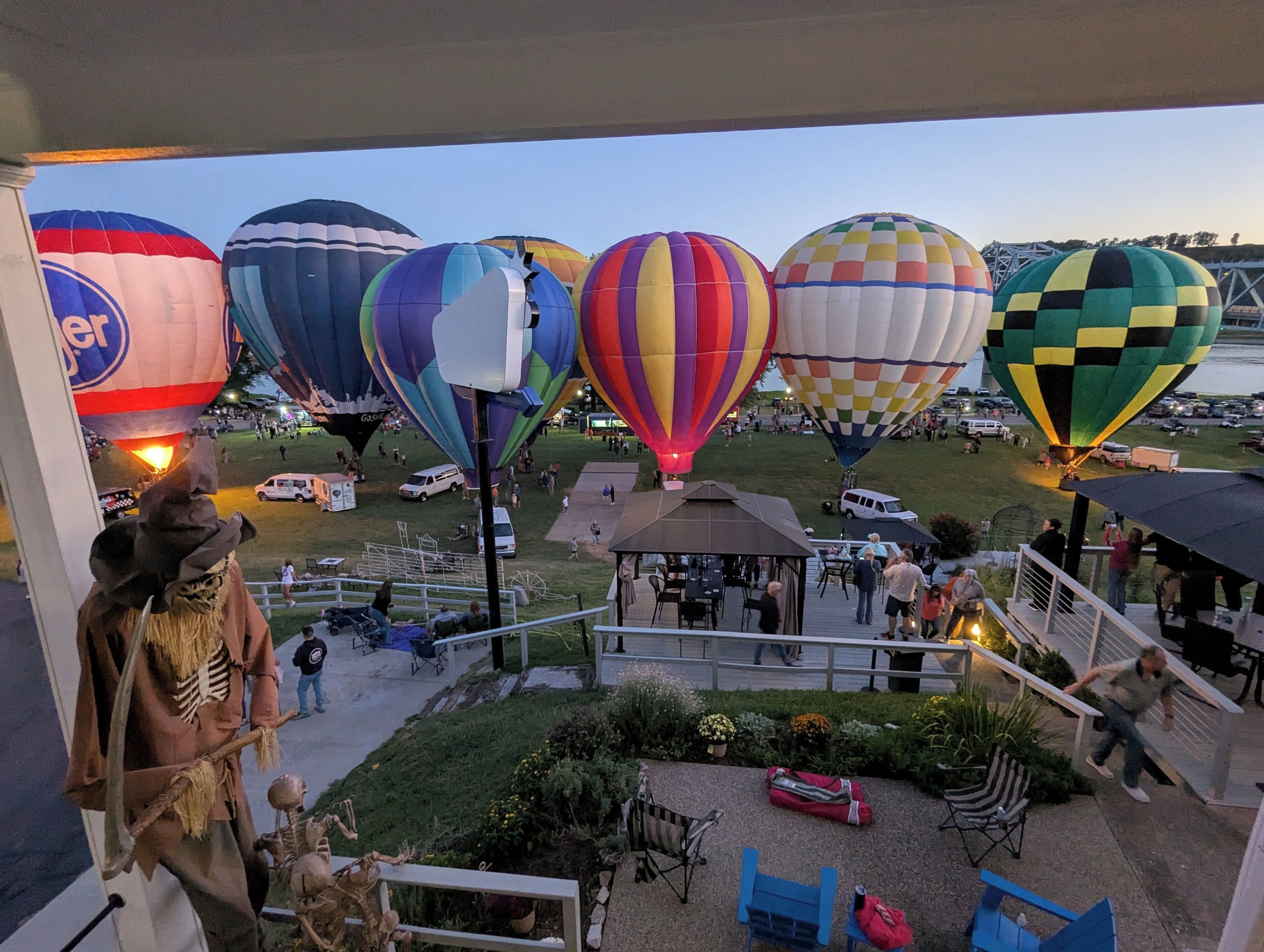 A balcony with a view of colorful hot air balloons and a skeleton figure.