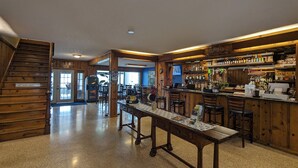 A bar area with wooden furnishings, a long table, and a staircase.