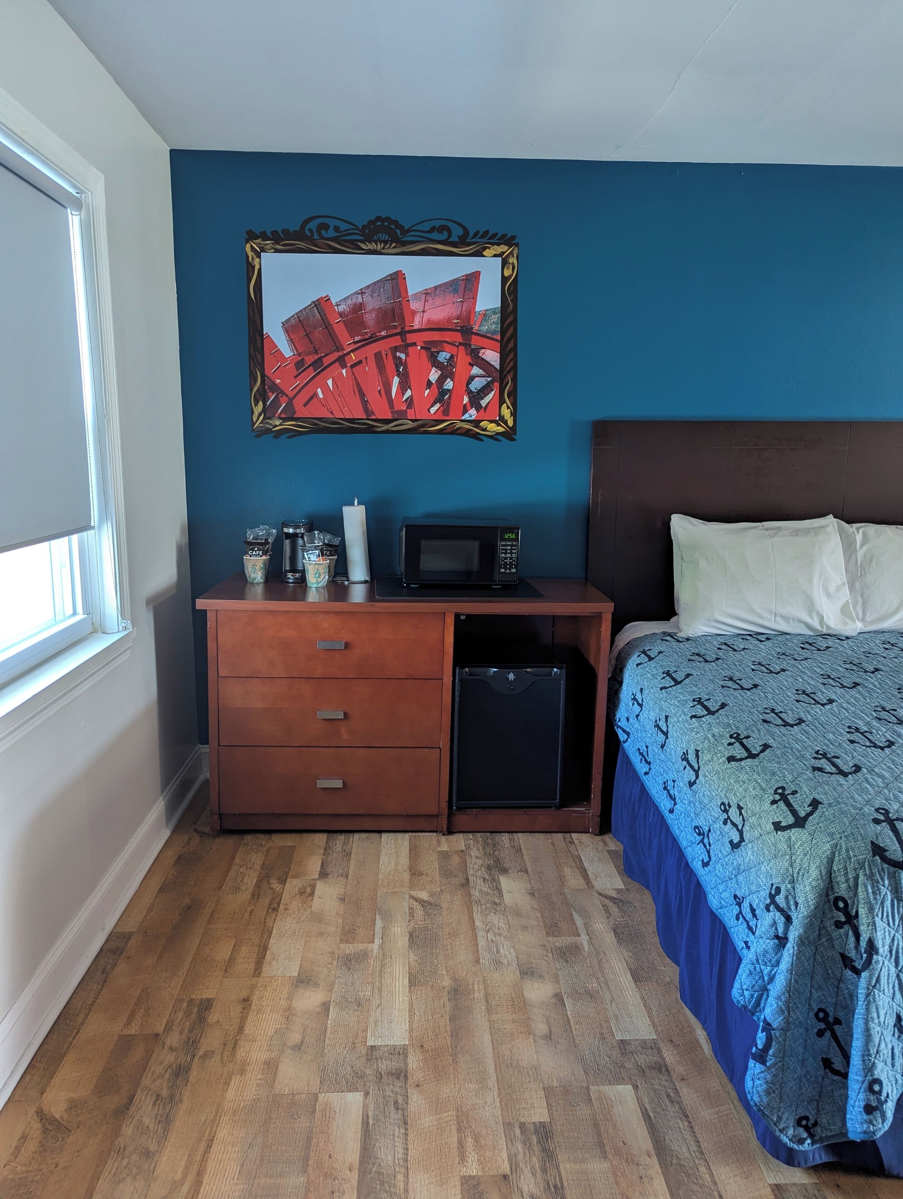 A bedroom with a bed, a dresser, a microwave, and a small refrigerator.