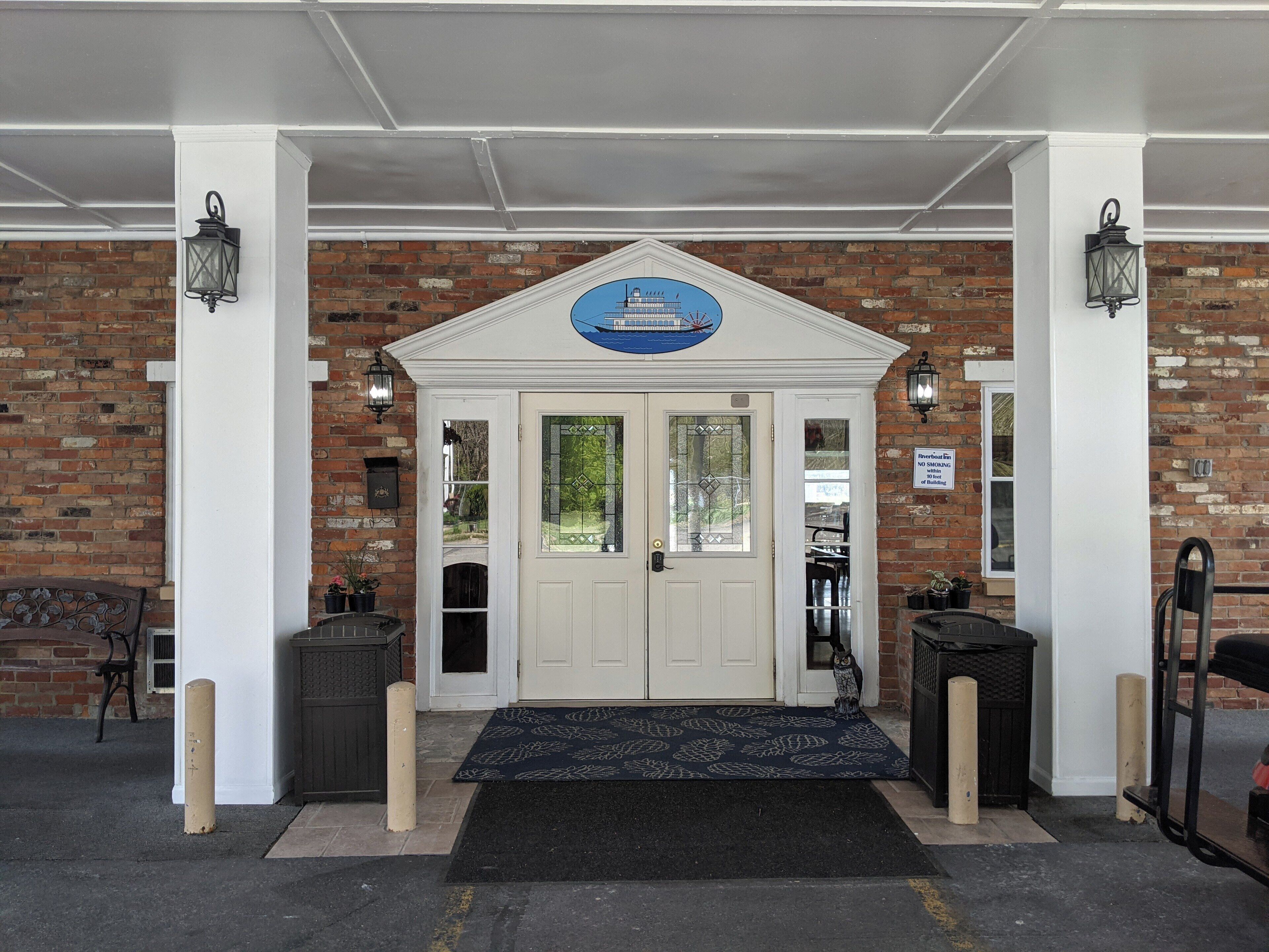 A building entrance with a white door, a blue sign above, and a brick wall.