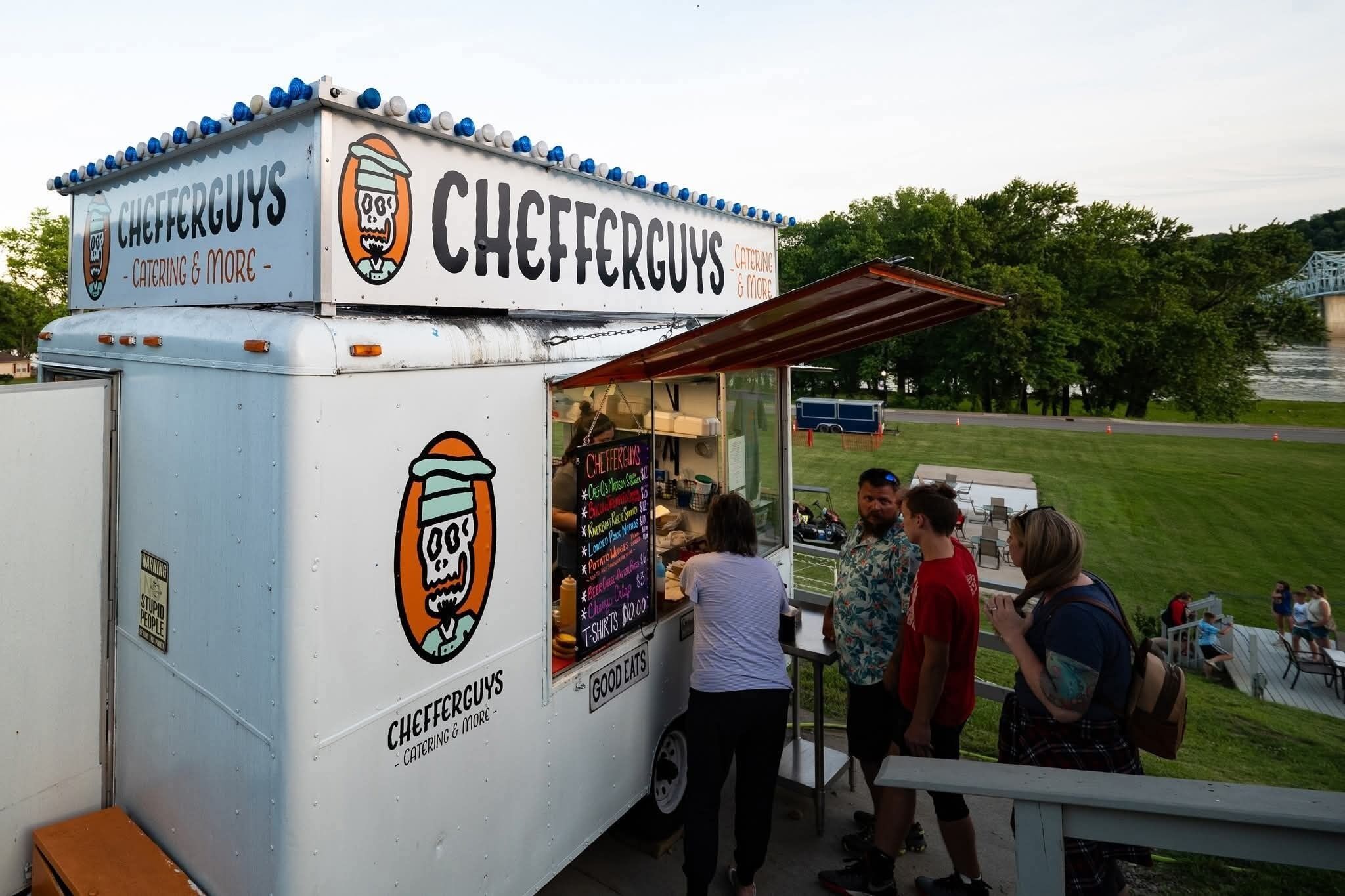 Un camion-restaurant appelé CHEFFERGUVS, doté d’un panneau affichant le menu et d’une fenêtre de service.