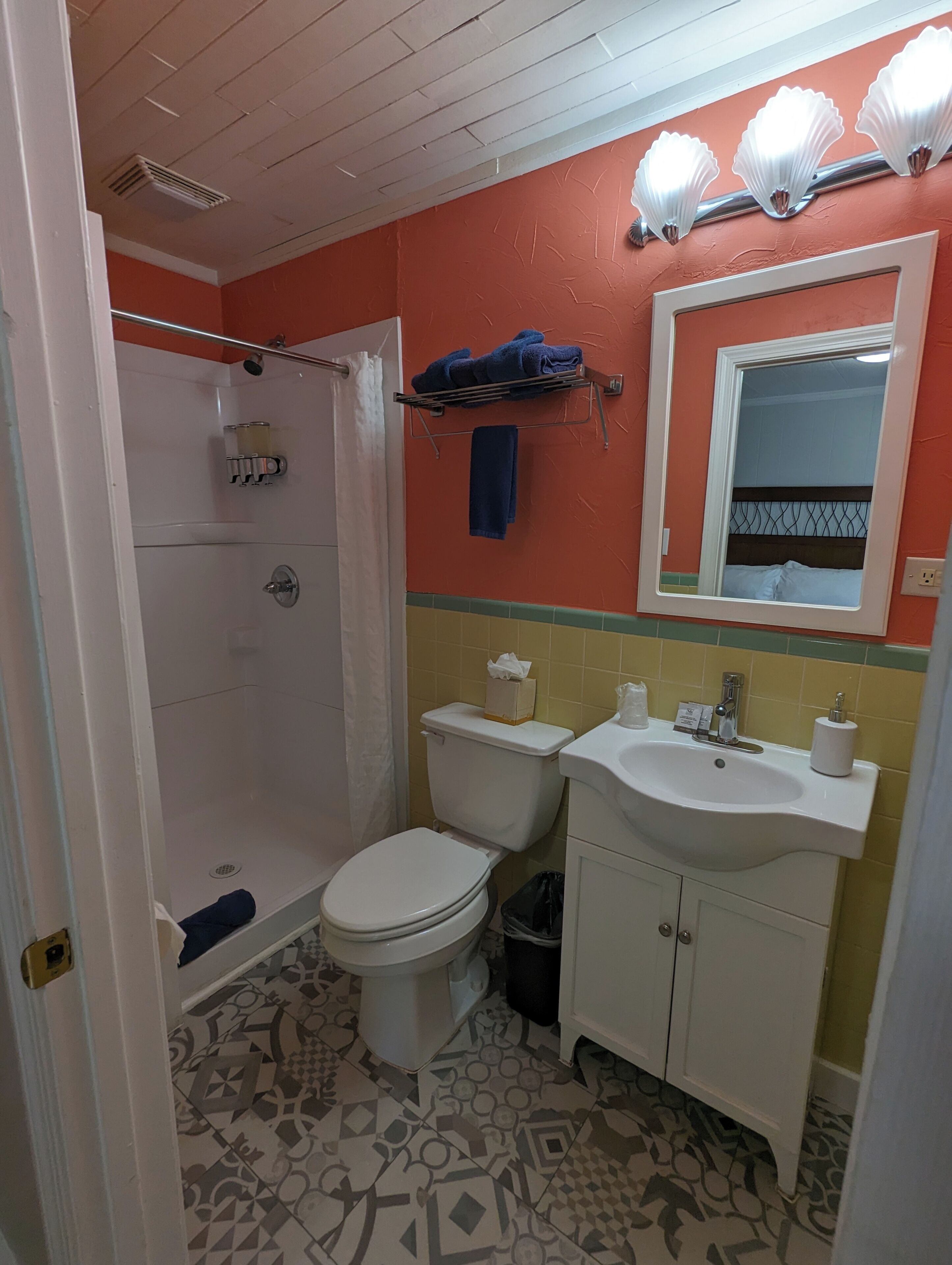 A bathroom with a shower, toilet, sink, and a mirror.