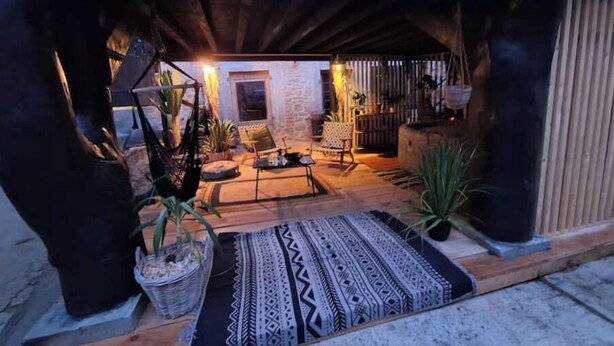 An interior view of a rustic-style living area with a stone wall, wooden furniture, and potted plants. - Atypical little gîte chez sam est gael  (Charix)