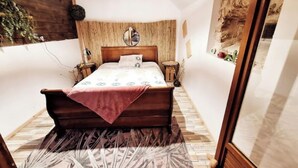 A bedroom with a wooden bed, a hanging light fixture, a mirror, and a view of the outside. - Atypical little gîte chez sam est gael  (Charix)