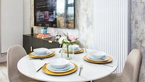 A dining area with a round table set for four, featuring gold-rimmed plates and a vase with flowers. - Apricot House- Cozy 2 Bedroom House in Birmingham (Birmingham)