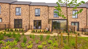 A row of modern brick townhouses with large windows and a well-maintained garden in the foreground. - Apricot House- Cozy 2 Bedroom House in Birmingham (Birmingham)