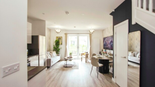 A modern living room with a sofa, dining table, and chairs. There is a staircase leading to another level. - Apricot House- Cozy 2 Bedroom House in Birmingham (Birmingham)