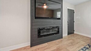 A modern living room with a flat-screen TV mounted above a fireplace. - Quiet & Private, Comfy Beds, Fire Pit, & Bikes

 (Portsmouth)