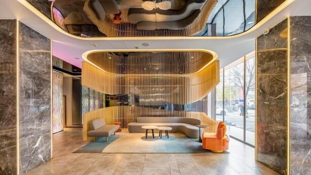A modern lobby with a curved wooden structure, a sofa, a coffee table, and a view of the outside. - Orange Hotel (Zhengzhou Hongzhuan Road) (Zhengzhou)