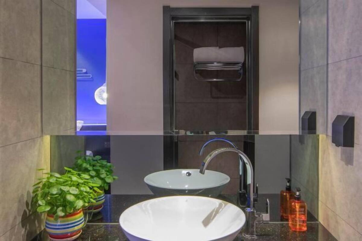 A modern bathroom with two sinks, a towel rack, and potted plants.