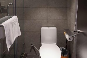 A modern bathroom with a white toilet, a glass shower enclosure, and a towel hanging on a rack. - Orange Hotel (Zhengzhou Hongzhuan Road) (Zhengzhou)