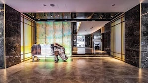 A modern lobby with marble flooring, a reception desk, and a glass partition with a colorful abstract design. - Orange Hotel (Zhengzhou Hongzhuan Road) (Zhengzhou)