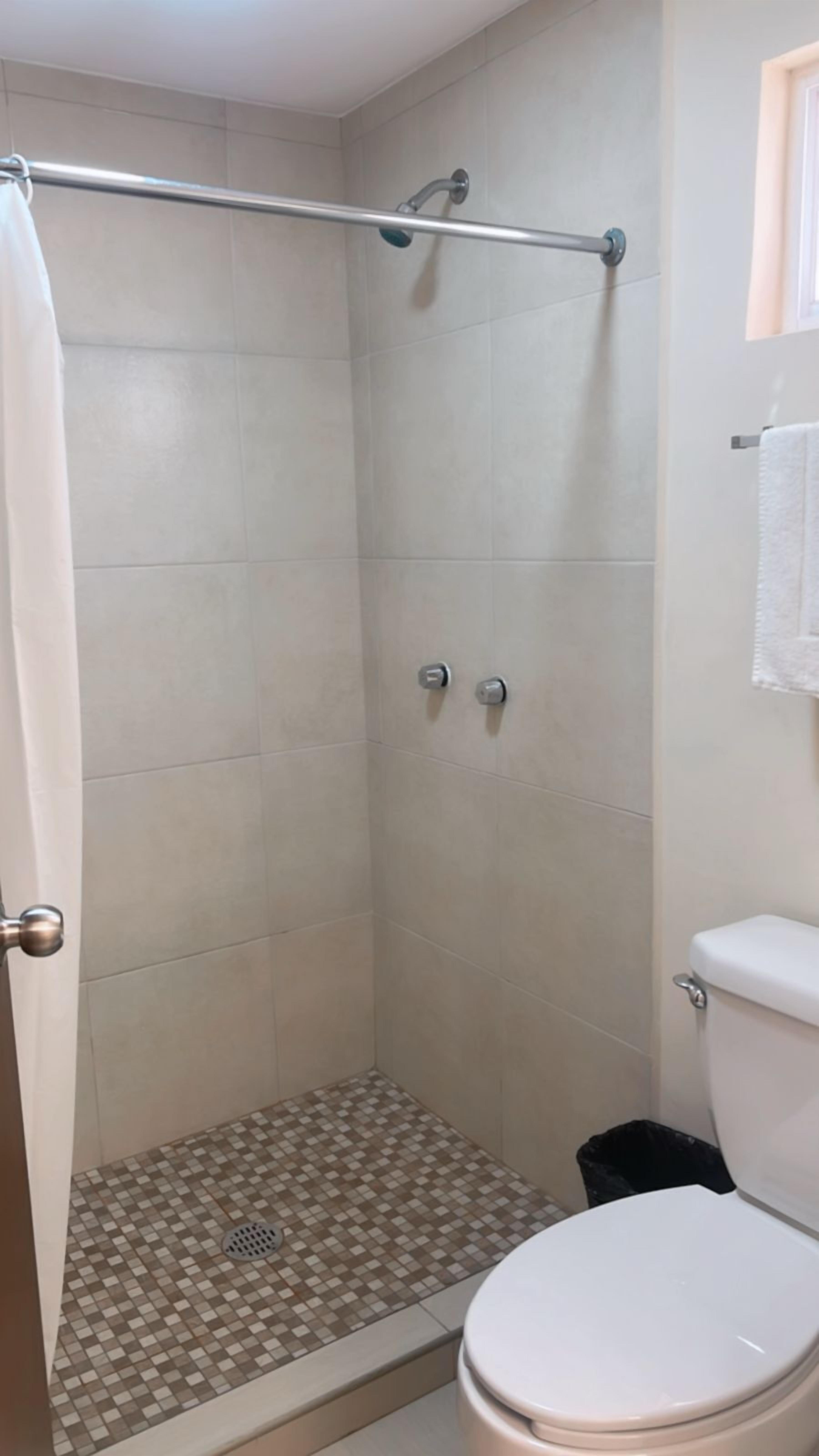 A shower with a checkered floor, a toilet, and a towel rack.