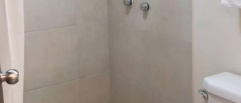A shower with a checkered floor, a toilet, and a towel rack.