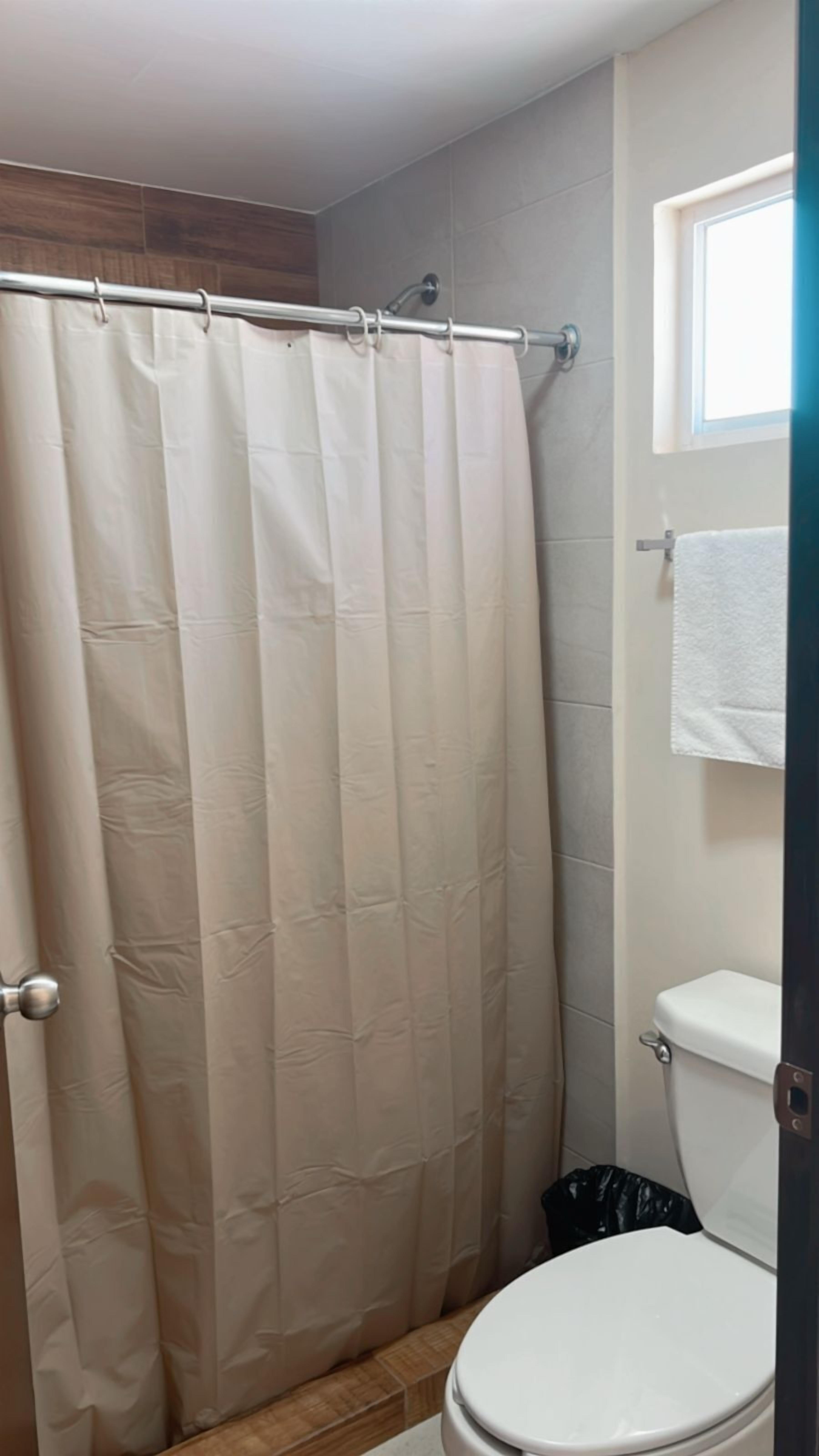 A bathroom with a shower curtain, a toilet, and a towel hanging on the wall.