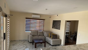 Una sala de estar moderna con un sofá modular, una mesa de centro y un comedor con sillas.