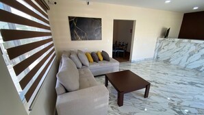 Una sala de estar con un sofá, una mesa de centro y suelo de mármol.