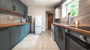A modern kitchen with grey cabinets, a white refrigerator, a washing machine, and a stove. - Monthly Savings - 4 Beds - Sleeps 8 - Free Parking (Southampton)