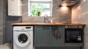 A compact kitchen with a built-in washer, oven, and a window with a view of greenery. - Monthly Savings - 4 Beds - Sleeps 8 - Free Parking (Southampton)
