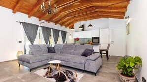 A modern living room with a grey sectional sofa, a round coffee table, and a wooden ceiling. - LA GRONDA Holiday House (Rovinj)