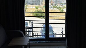 A room with a large window offering a view of a cityscape, including tall buildings and a construction site. - Deluna Yaşamkent (Ankara)