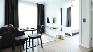 A modern hotel room with a dining area, a TV mounted on the wall, and a bed with a view of the outdoors. - Deluna Yaşamkent (Ankara)