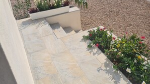 A paved outdoor area with a car parked in the background, surrounded by gravel and greenery. - Rent mini villa between sea and mountains... (VENTISERI)