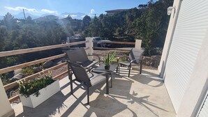 A patio with outdoor furniture, a potted plant, and a view of the surrounding landscape. - Rent mini villa between sea and mountains... (VENTISERI)