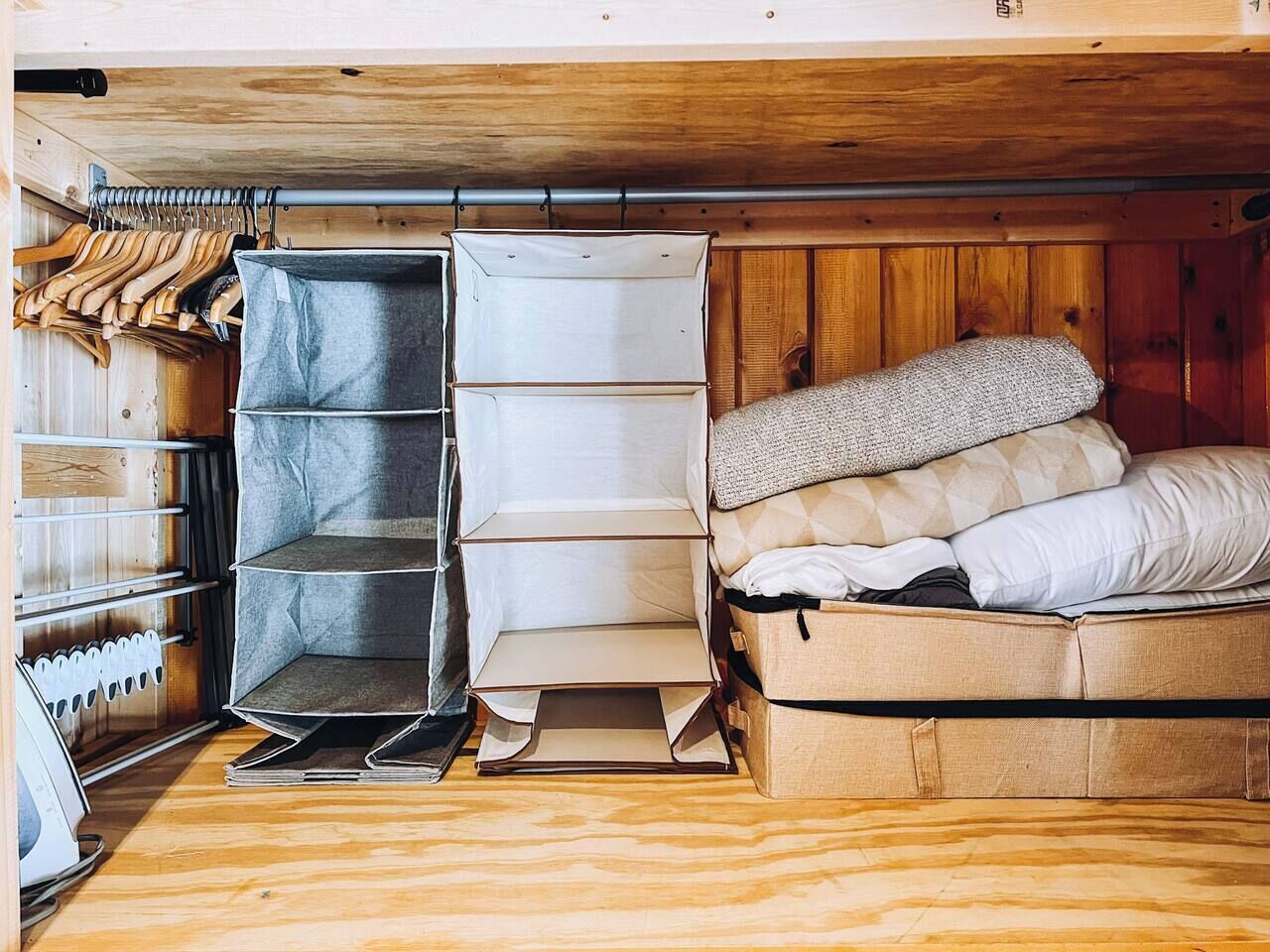 Une petite pièce comprenant un lit, une petite armoire et un porte-chaussures.