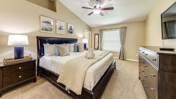 A bedroom with a bed, nightstands, a dresser, a ceiling fan, and framed pictures on the wall. - 638 - Beautiful Pool Villa Highlands Reserve Newly Modernised 4 Bed Property (Davenport)