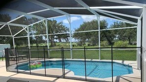 A covered swimming pool with a safety fence, lounge chairs, and a view of the surrounding landscape. - 638 - Beautiful Pool Villa Highlands Reserve Newly Modernised 4 Bed Property (Davenport)